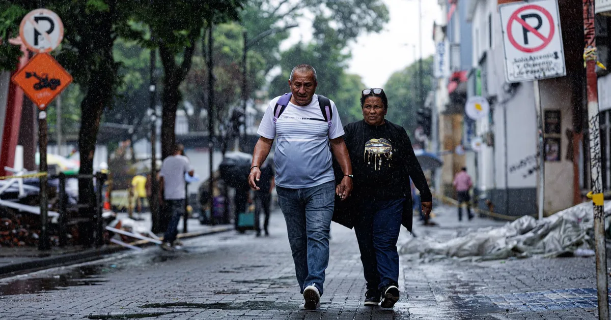 Dos personas caminando por una calle de una ciudad colombiana.
