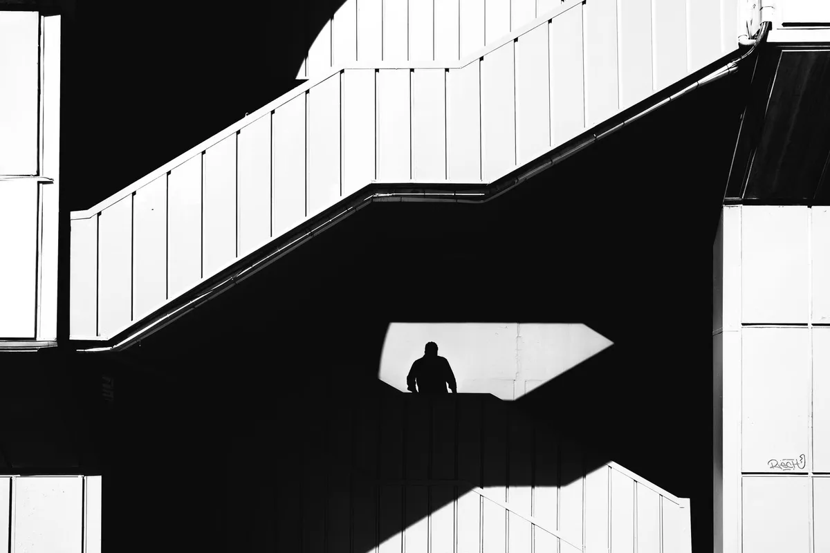 Silueta de una persona subiendo unas escaleras, en blanco y negro.