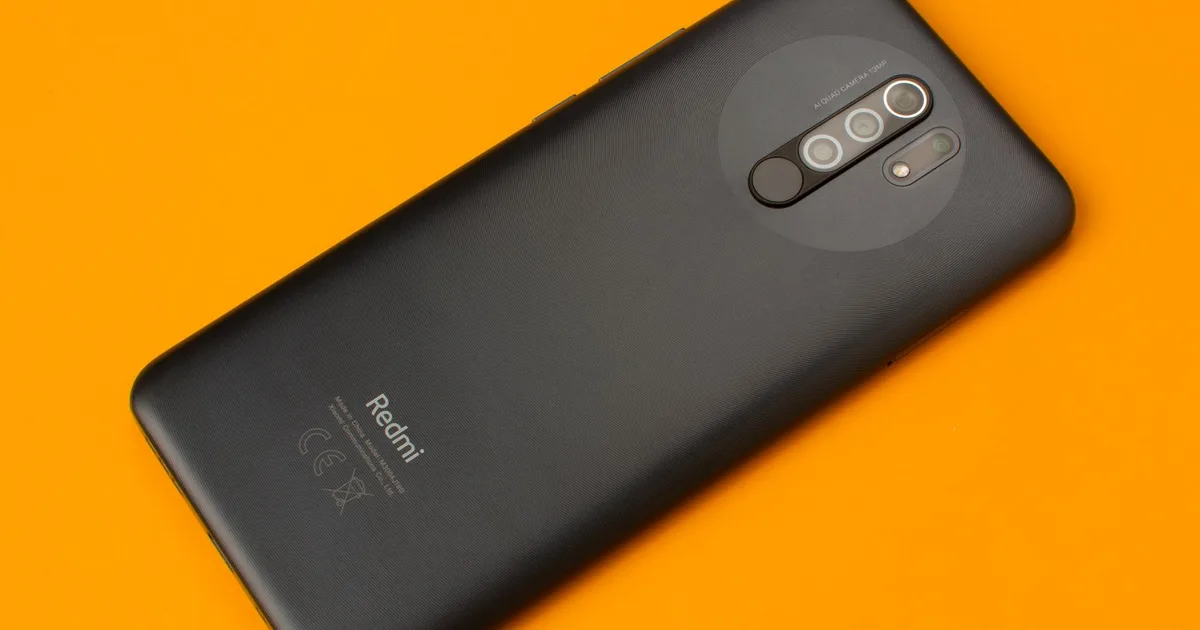 Celular Xiaomi Redmi visto por detrás sobre fondo naranja.